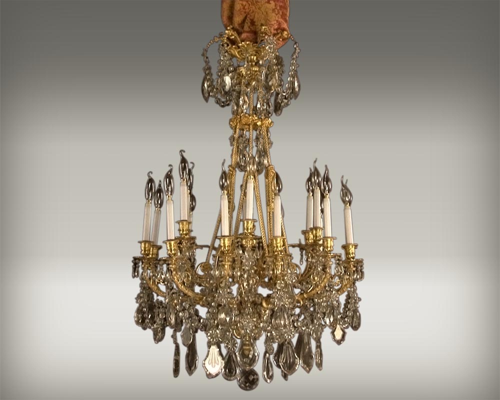 Lustre à cristaux à 12 bras et 18 lumières , décors de passementeries en bronze doré. Lustre à cristaux à 12 bras et 18 lumières , décors de passementeries en bronze doré.-0