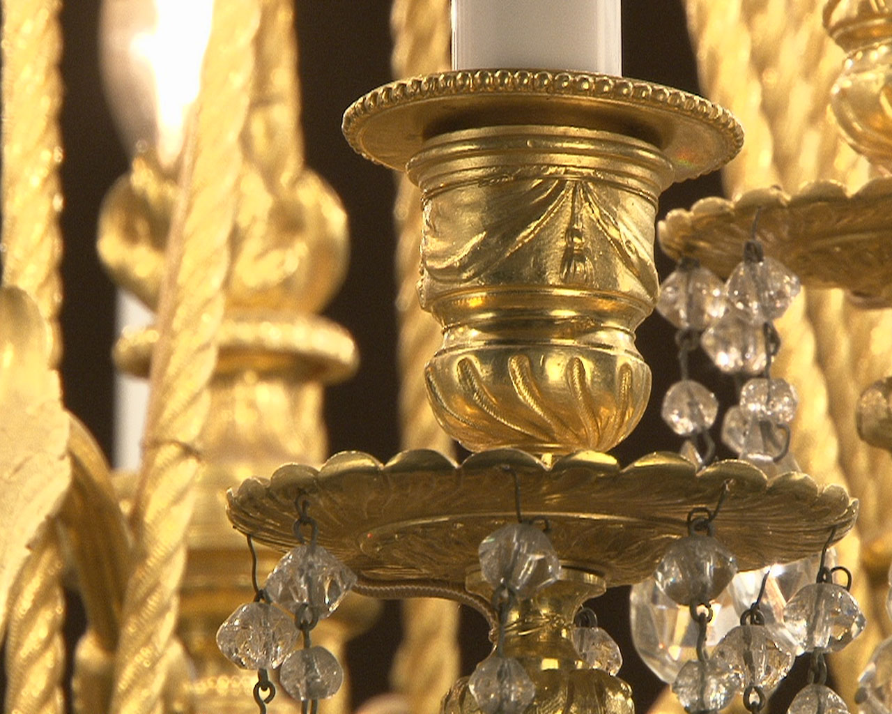 Lustre à cristaux à 12 bras et 18 lumières , décors de passementeries en bronze doré. Lustre à cristaux à 12 bras et 18 lumières , décors de passementeries en bronze doré.-15