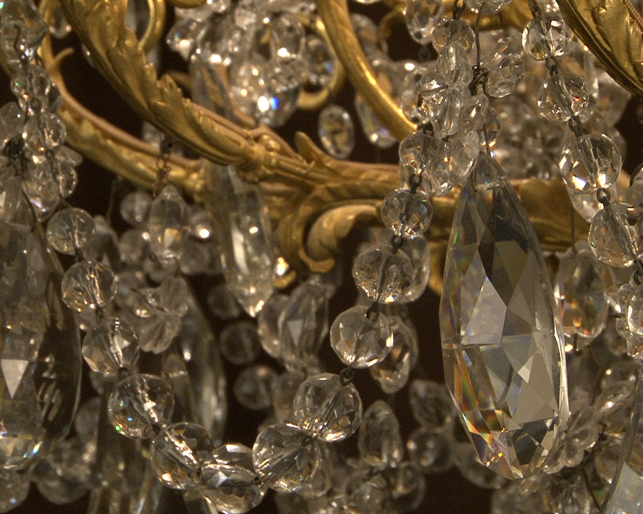 Lustre à cristaux à 12 bras et 18 lumières , décors de passementeries en bronze doré. Lustre à cristaux à 12 bras et 18 lumières , décors de passementeries en bronze doré.-16