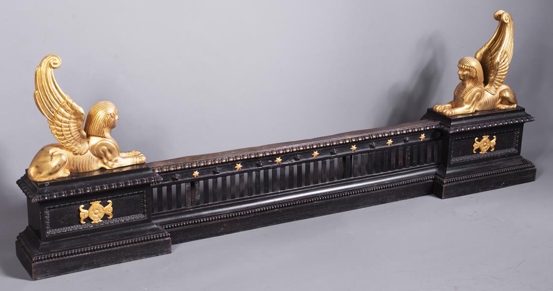 Barre de chenets aux sphinx ailés en bronze à deux patines Barre de chenets aux sphinx ailés en bronze à deux patines-1