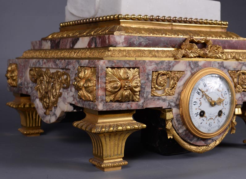 Pendule en marbre fleur de pêcher et bronze doré surmontée d’une sculpture en marbre   blanc statuaire représentant Phryné devant ses juges signée « Campagne », vers 1900 Pendule en marbre fleur de pêcher et bronze doré surmontée d’une sculpture en marbre   blanc statuaire représentant Phryné devant ses juges signée « Campagne », vers 1900-10