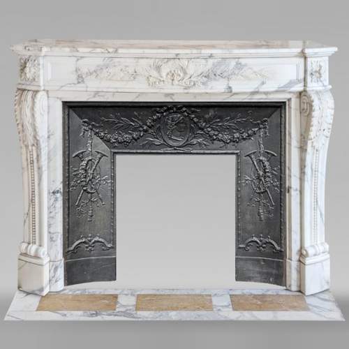 Cheminée de style Louis XVI galbée en marbre Arabescato décorée d'une couronne de laurier