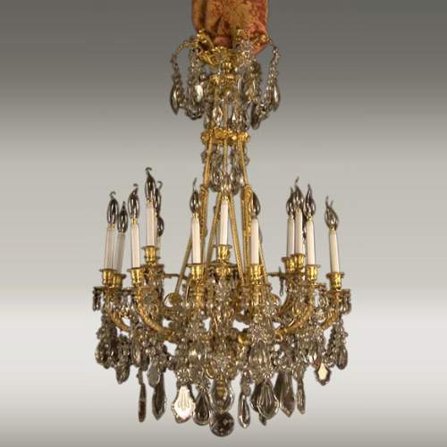 Lustre à cristaux à 12 bras et 18 lumières , décors de passementeries en bronze doré.