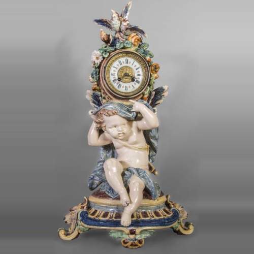 Pendule en faïence polychrome, à décor de Cupidon soutenant le cadran