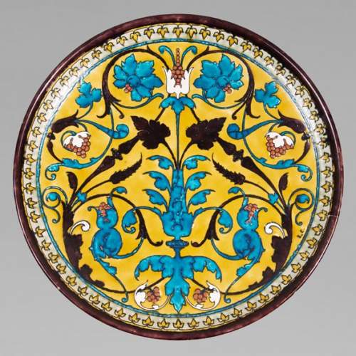 Théodore DECK (1823-1891) - Plat rond en céramique à décor oriental d'un vase fleuri et rinceaux feuillagés sur fond jaune