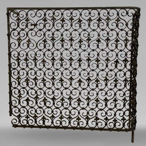 Grille de radiateur en fer forgé ornée de volutes et de fleurs de lys