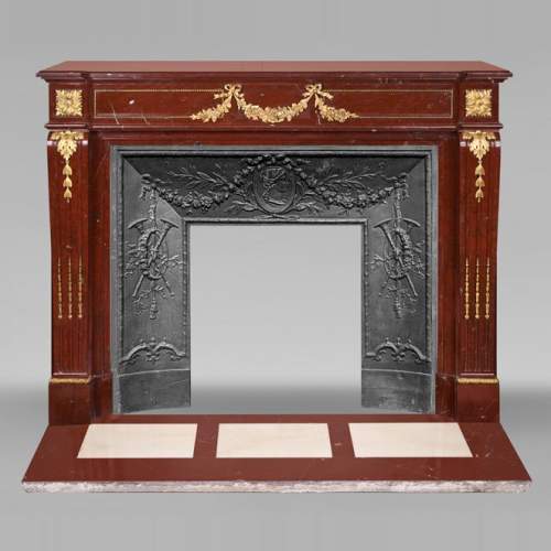 Cheminée de style Louis XVI en marbre Rouge Antique, à bronzes, décorée d'une guirlande