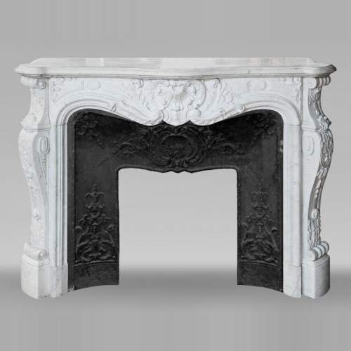 Cheminée de style Louis XV très sculptée en marbre de Carrare, coquille feuillagée.