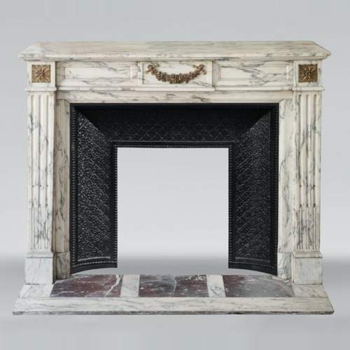 Cheminée de style Louis XVI en marbre d'Arabescato décorée d'une guirlande de fleurs en bronze doré