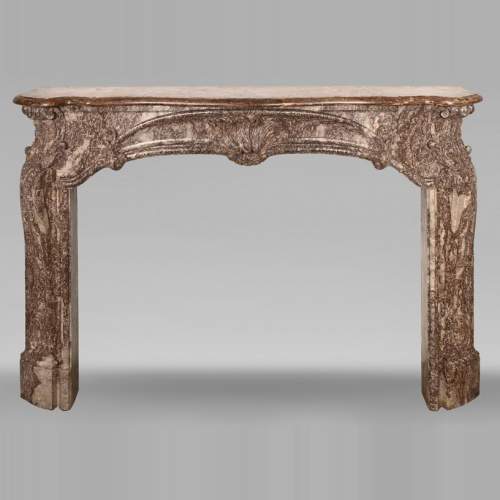 Cheminée d'époque Louis XV ornée d'une palmette asymétrique dans une variation de marbre Rouge Royal