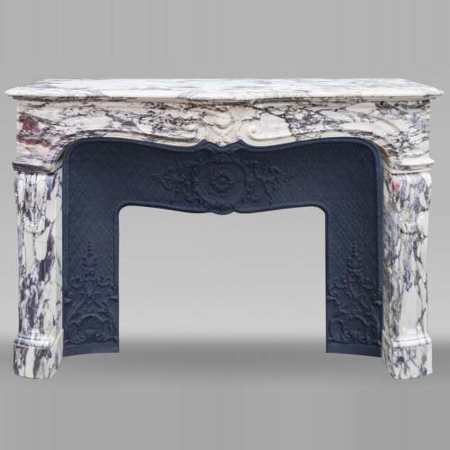 Cheminée de style Louis XV en Brèche Violette, au cartouche central encadré de palmettes