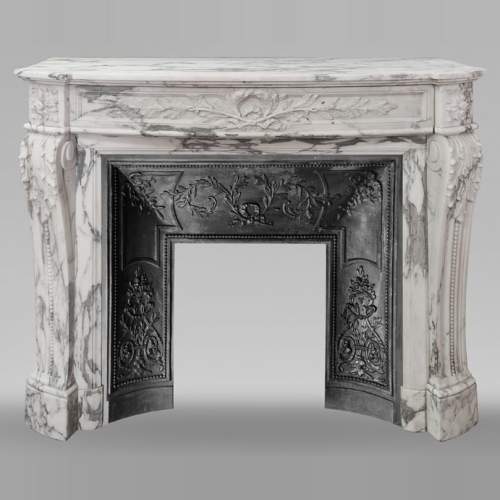 Cheminée galbée de style Louis XVI en marbre Arabescato, ornée d'une couronne de laurier