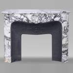 Cheminée de style Régence en brèche violette, décorée d'une grosse coquille